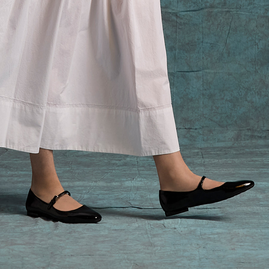 Person wearing black shoes and a white skirt on a textured blue floor.