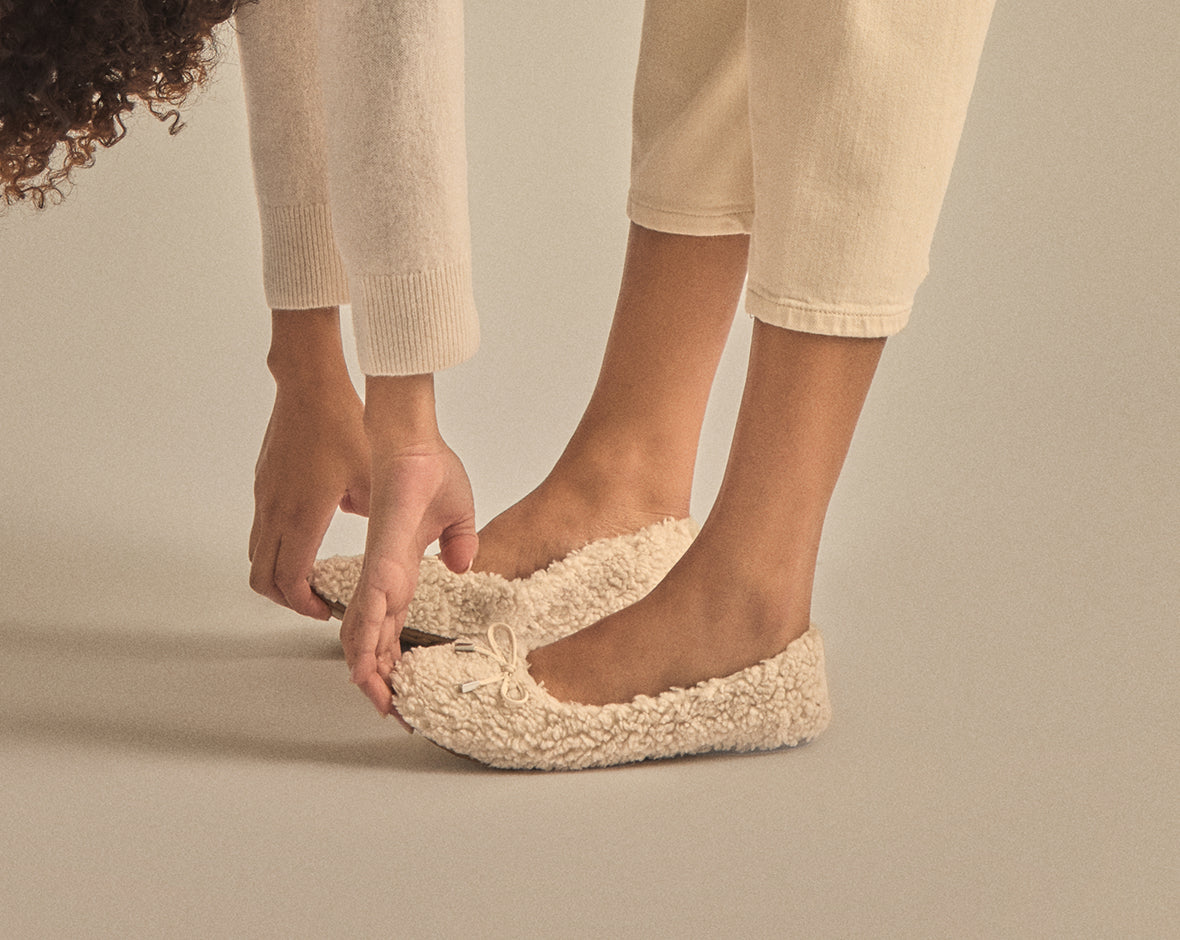 Person wearing beige shearling-lined patrina flats on a neutral background