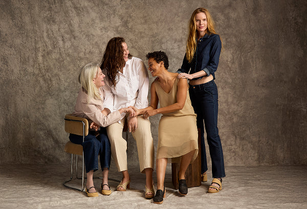 Four women interacting in a studio setting with a gray background