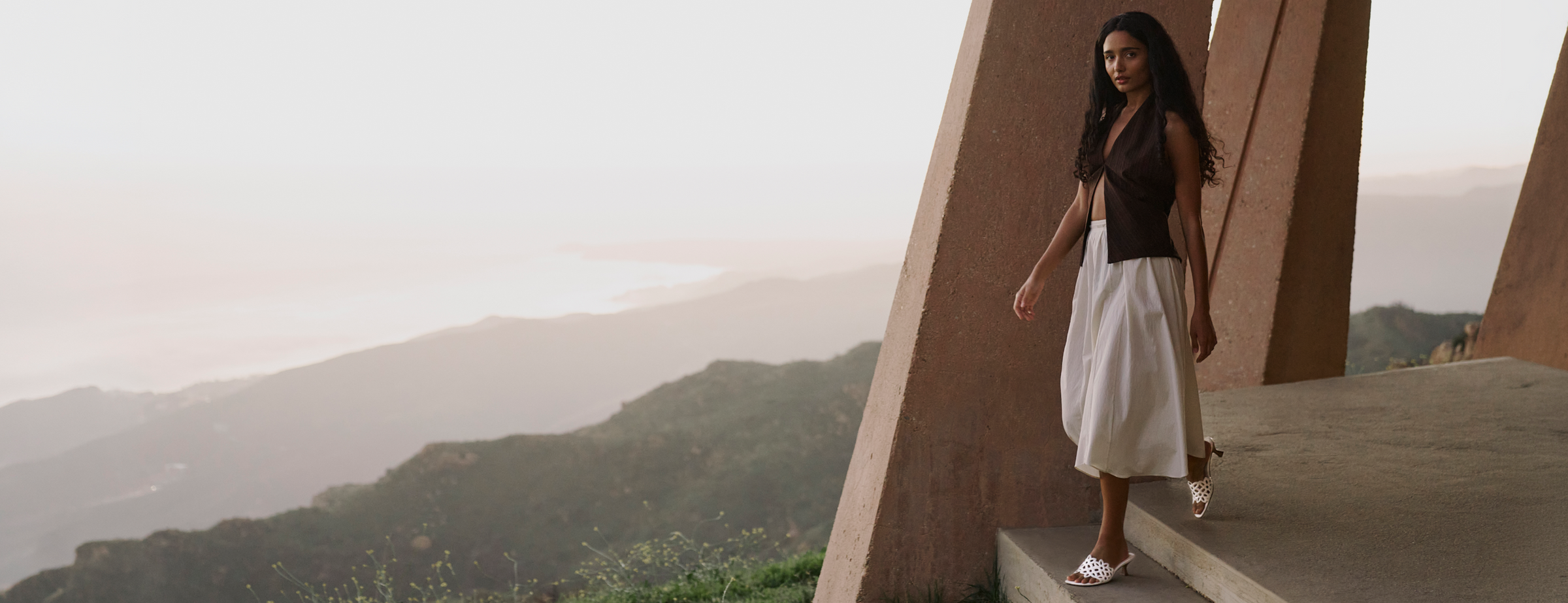 Woman standing on a high vantage point with mountains in the background