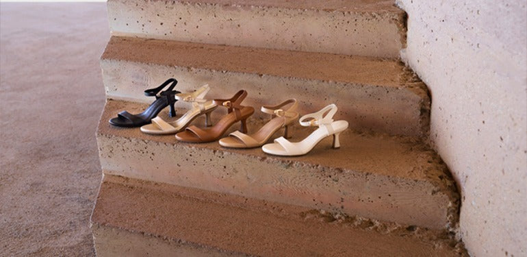 Set of high-heeled shoes arranged on a set of concrete stairs.