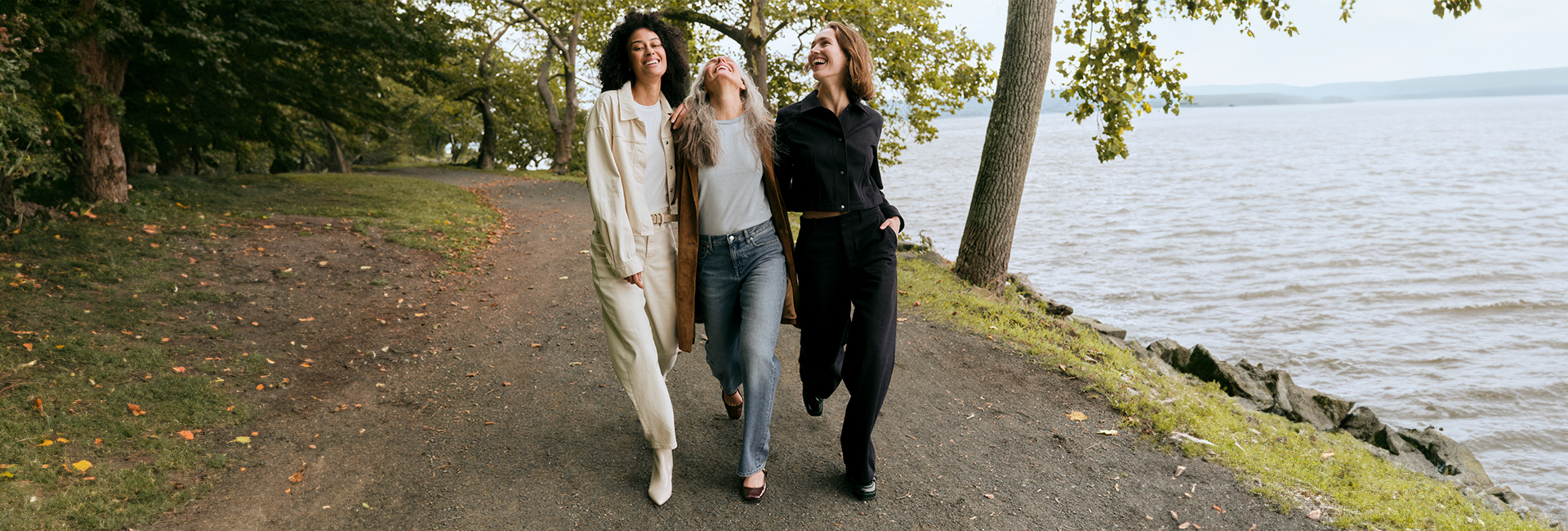 3 women walking on path next to river