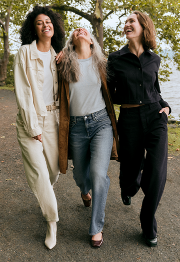 3 women walking on path next to river